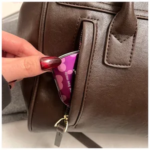 Detalle de bolso tote de cuero suave con bolsillo lateral de cremallera metálica