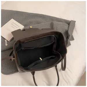 Vista detallada del interior del bolso tote marrón con compartimentos y hebilla dorada