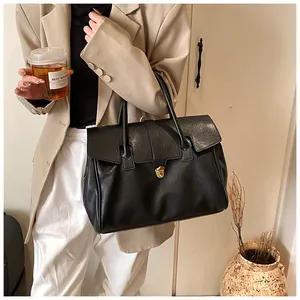 Vista detallada de un bolso tote negro de cuero suave llevado por una modelo real.
