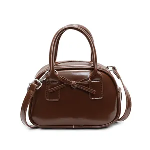Brown bow-knot bowling handbag with detachable strap for women on white background