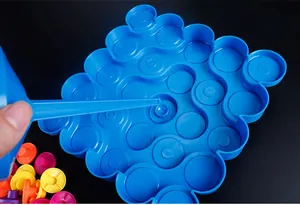 Detail of hand placing colorful pegs into a blue plastic balancing tower base
