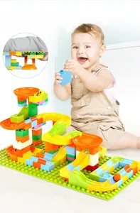 Baby playing with colorful large particle ball track blocks on a green baseplate