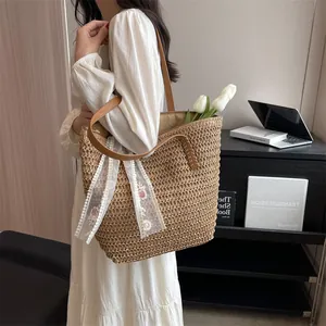 Close-up of straw tote bag showing detailed floral lace ribbon and brown leather strap