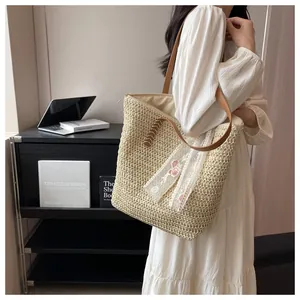 Detail of straw tote bag with lace trim, floral ribbons and brown leather handles