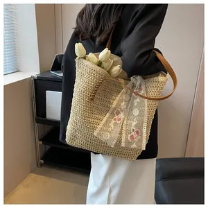 Detail of straw tote bag with floral lace ribbon and brown leather shoulder straps