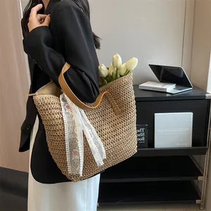 Straw tote bag detail with woven texture and white floral lace scarf on model's shoulder