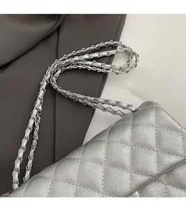Detailed close-up of silver quilted leather chain bag with pebbled texture and metal strap