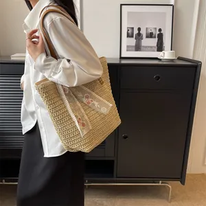 Detail of woven straw tote bag featuring delicate lace ribbon and floral embroidery