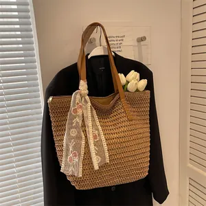 Detail of woven straw tote bag featuring brown leather handles and floral lace scarf