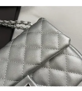 Detail of silver crossbody bag featuring quilted caviar texture and metal chain strap