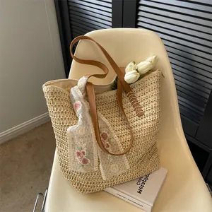 Close-up of straw woven tote with brown leather handles and decorative lace scarf detail