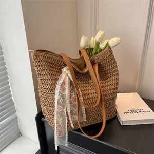 Detail of a large straw tote bag with floral lace ribbon and brown leather handles