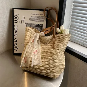 Beige straw tote bag with brown leather handles and red floral lace scarf on a table