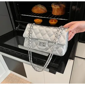 Detailed view of silver quilted crossbody bag with metal chain strap and turn-lock closure