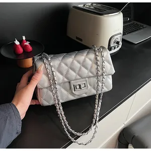 Close-up of a silver quilted chain bag with metallic finish and metal lock detail