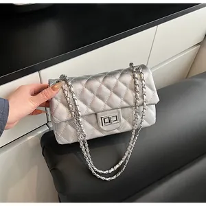 Close-up of silver quilted crossbody bag with rhombic pattern and metal chain strap