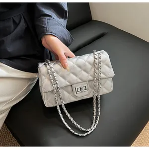 Detail shot of silver quilted leather flap bag with metallic chain strap on dark leather
