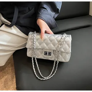 Detail of silver quilted crossbody bag with metallic chain strap and twist lock