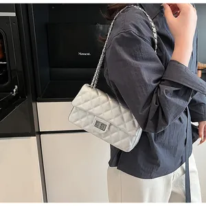 Detail of silver metallic quilted chain bag with turn-lock closure on female model