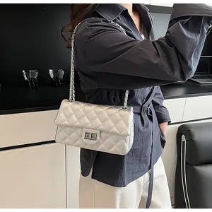 Detail of silver quilted leather texture and metallic chain strap on crossbody bag