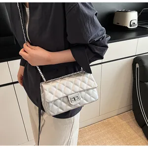 Detail of silver quilted crossbody bag with metal chain strap and turn-lock closure