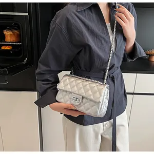 Close-up of silver quilted crossbody bag with metal chain strap and turn-lock closure
