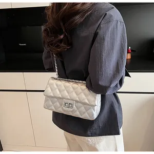 Detail of silver quilted crossbody bag with metal chain strap and turn-lock closure