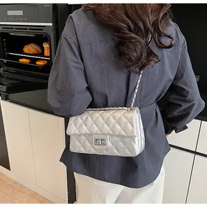 Close-up of silver quilted crossbody bag with chain strap worn in a modern kitchen