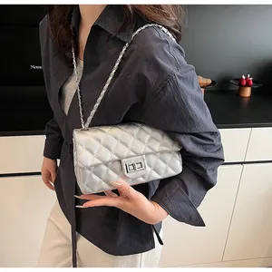 Detail of silver quilted crossbody bag featuring metal chain and turn-lock closure