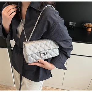 Detail shot of silver quilted chain bag with sleek metal turn-lock and leather chain strap