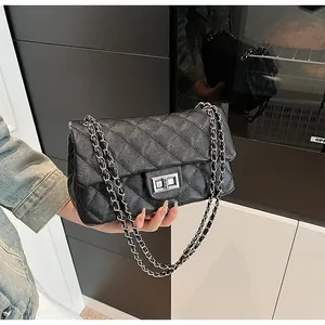 Detailed macro view of black quilted caviar leather and silver rectangular turn-lock closure