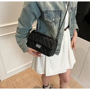 Detailed view of black quilted crossbody bag with silver clasp and leather chain strap