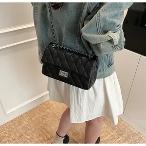 Close-up of black quilted shoulder bag with silver chain strap and metal turn-lock