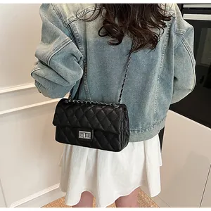 Detail of black quilted chain shoulder bag with silver clasp and lychee leather texture