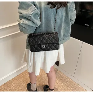 Detail of a black quilted chain crossbody bag with silver twist lock and woven strap