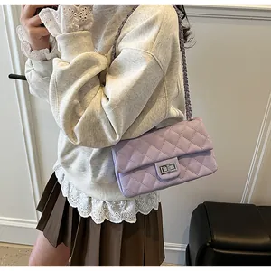 Detail of lavender quilted crossbody bag with silver chain strap shown on a model