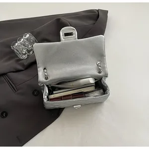 Detail of silver quilted crossbody bag showing interior capacity with phone and wallet