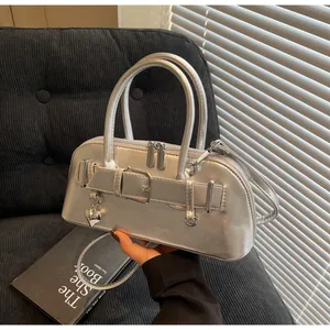 Détail d'un sac à main argenté avec sangle à boucle en cuir et pendentif en cœur