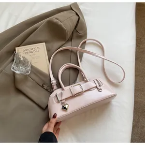 Détail du mini sac en cuir verni rose clair avec boucles argentées sur lit blanc