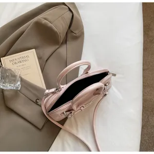 Détail d'un sac à main en cuir verni rose clair avec boucle et double poignées