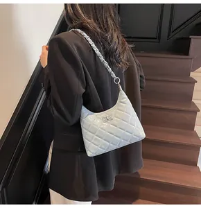Détail du sac à épaule matelassé bleu clair avec bandoulière chaîne élégante et fermoir tourniquet.