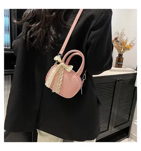 Detailed shot of pink mini crossbody bag with cream lace bow accent on a dark jacket