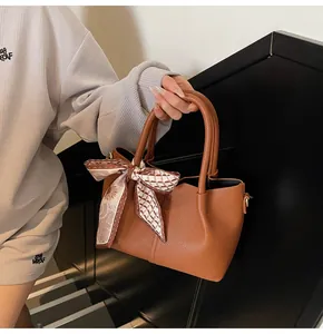 Détail du sac seau marron avec motif litchi et foulard en soie vintage imprimé