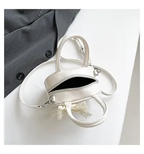 Detail of white mini crossbody bag with a delicate lace bow and sleek leather texture