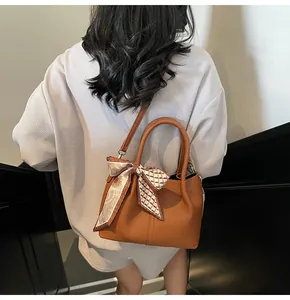 Détail du sac seau marron avec texture litchi, poignée en foulard imprimé et bandoulière