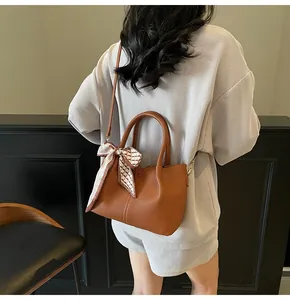 Détail du sac seau caramel grainé litchi avec une poignée décorée d'un foulard en soie à carreaux