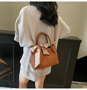 Détail du sac seau en cuir grainé caramel avec foulard décoratif en soie fleurie