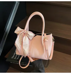 Détail d'un sac à main rose grainé avec foulard en soie et fermoir métallique précis
