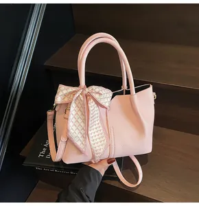 Détail d'un sac à main rose en cuir grainé avec une poignée ornée d'un foulard en soie