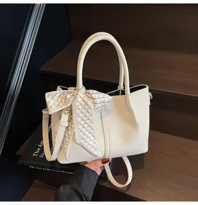 Détail du sac seau en cuir grainé blanc crème avec foulard en soie sur un escalier